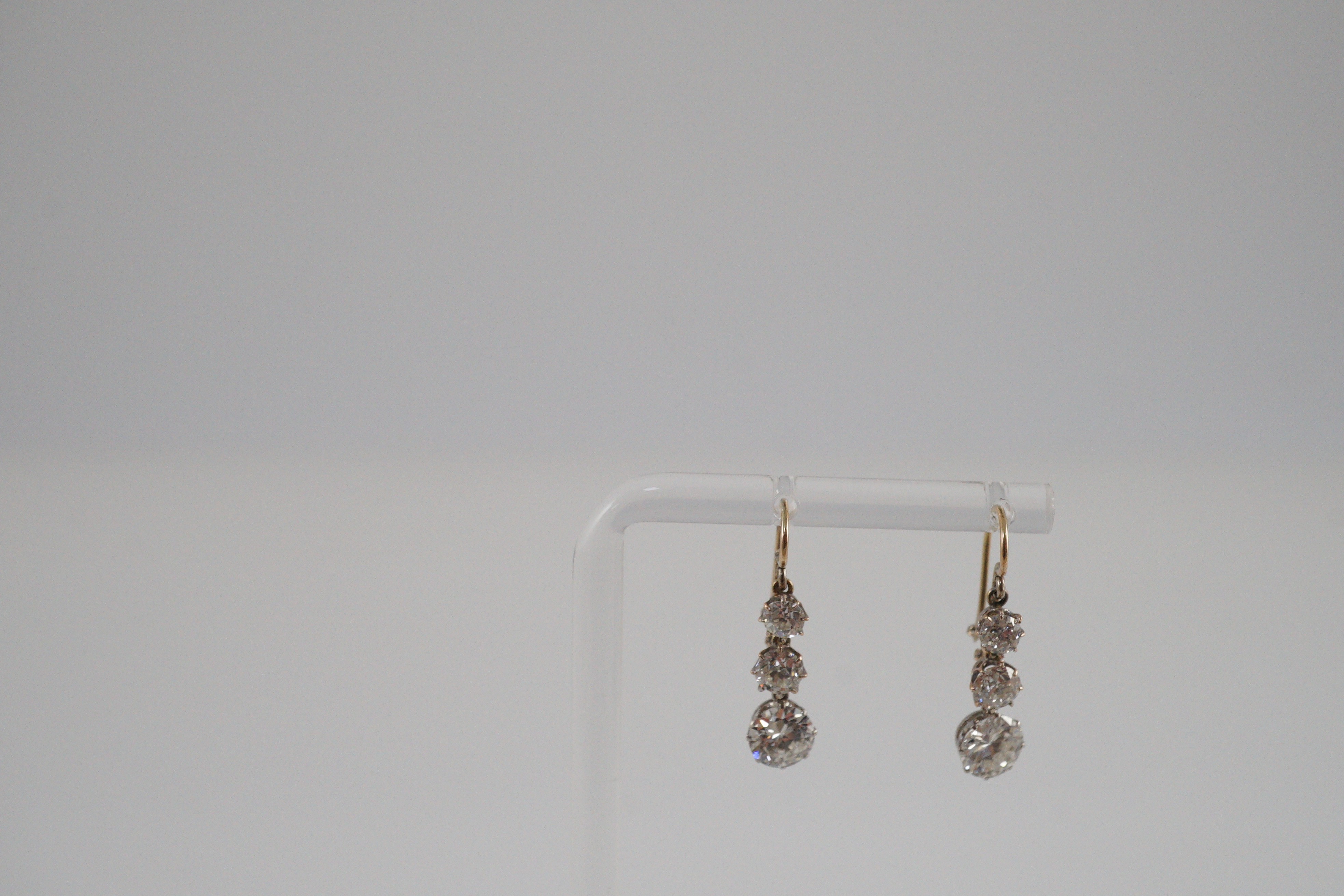 A pair of early to mid 20th century gold, platinum and graduated three stone diamond set drop earrings